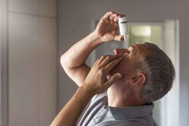 A man is using a eye drops for vision health.